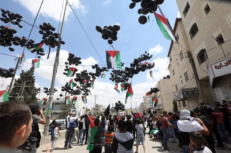 Palestinos lanzaron globos negros que llevaban banderas de Palestina, durante una protesta en Cisjordania. (Foto Prensa Libre: EFE)