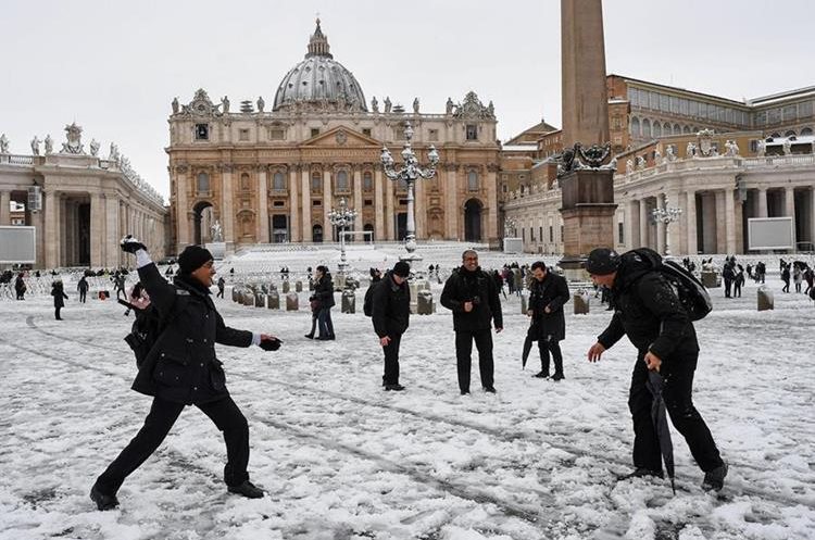 Turistas se lanzan bolas de nieve en la Plaza de San Pedro en el Vaticano, en una muy inusual imagen. (Foto Prensa Libre: EFE)