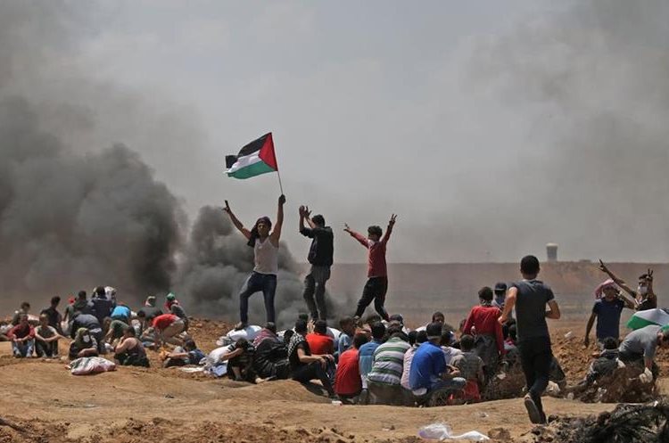 Manifestantes ondean una bandera palestina durante las protestas en la Franja de Gaza. (Foto Prensa Libre: AFP)