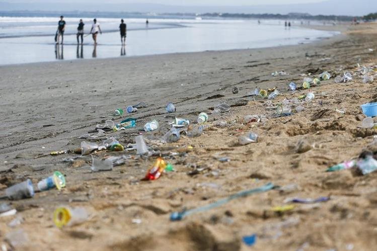 Varias personas caminan a la orilla del mar en Bali, Indonesia, en un área contaminada por desechos plásticos. (Foto Prensa Libre: EFE).