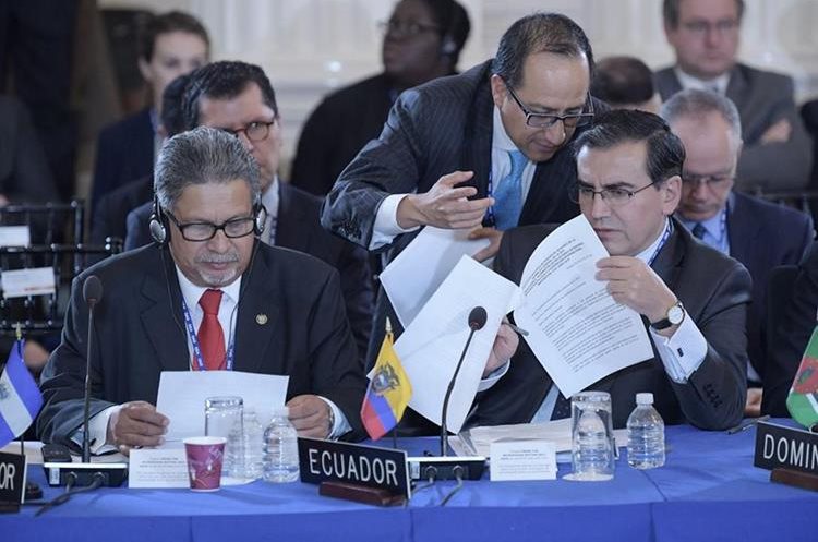 Los embajadores ante la OEA, Carlos Calles Catillo (i) de El Salvador, y José Valencia Amores (d) de Ecuador, leen unos documentos durante Asamblea. (EFE).