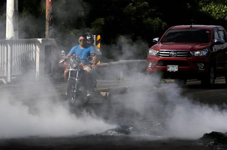 Un motociclista se ve bloqueado por el humo de la quema de neumáticos, en la ciudad de Sebaco, a unos 100 km de Managua. (AFP).