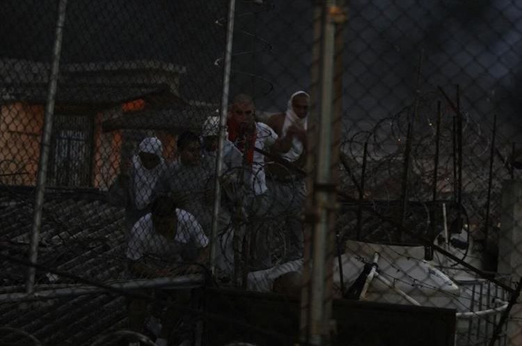Internos caminan por el techo. Al fondo, un incendio. (Foto Prensa Libre: Paulo Raquec)