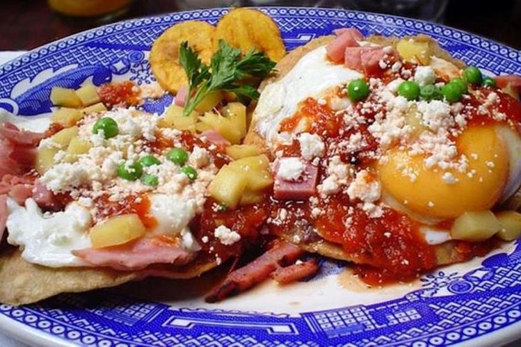 Una delicia de Yucatán: huevos motuleños, que son fritos y servidos sobre una tostada con frijoles negros, salsa de tomate, jamón y chícharos, con plátano, queso y salsa picante. OTHER