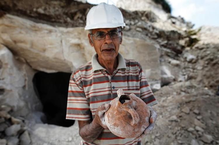 Un arqueólogo muestra un tipo de vasija hallado en excavación. (Foto Prensa Libre: AFP)