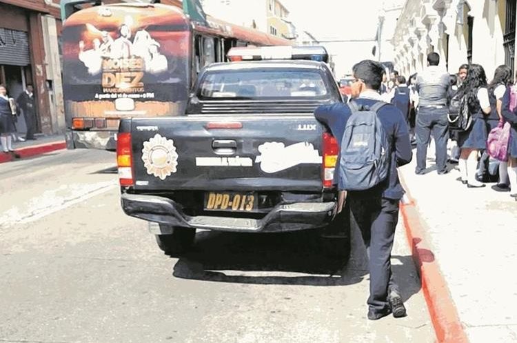 Un estudiante descansa recostado en una patrulla que resguarda un centro educativo en la zona 1. (Foto Prensa Libre: Hemeroteca PL)