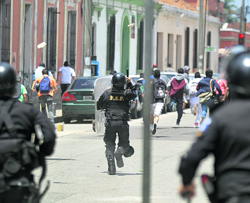 Un grupo de estudiantes huyen mientras le lanzan piedras a un grupo de policías antimotines, en la zona 1. (Foto Prensa Libre: Hemeroteca PL)