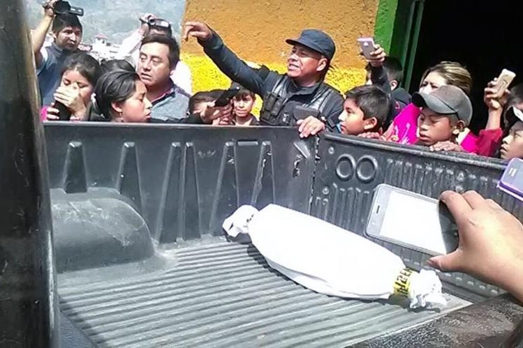 Curiosos permanecen junto a patrulla de la PNC que traslada feto localizado en Nebaj. (Foto Prensa Libre: Óscar Figueroa).