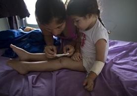 Ashley Pacheco recibe atenciones de su madre Oriana, en un hospital de Venezuela. (Foto Prensa Libre: AP).