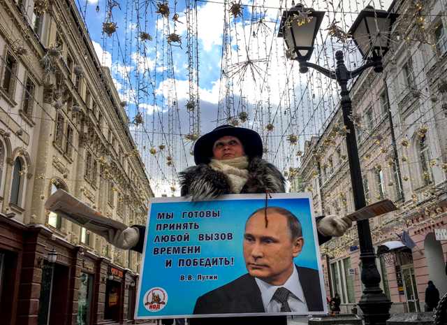 Un activista distribuye folletos electorales en apoyo del candidato presidencial el presidente Vladimir Putin en una calle del centro de Mosc