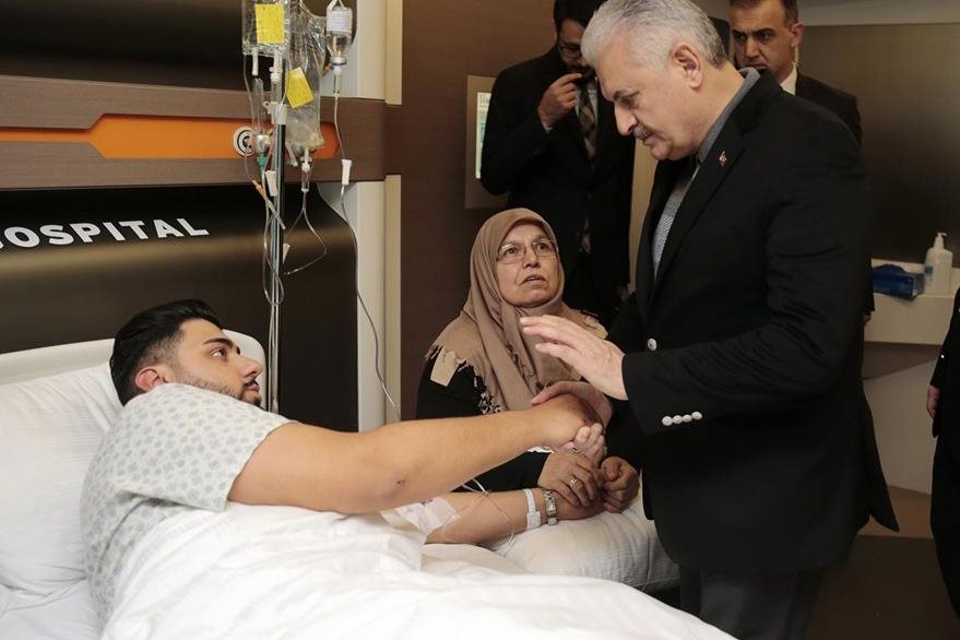 El primer ministro turco Binali Yildirim (d), habla con un herido en el hospital de Estambul, done efectó una visita. (Foto Prensa Libre: AP).